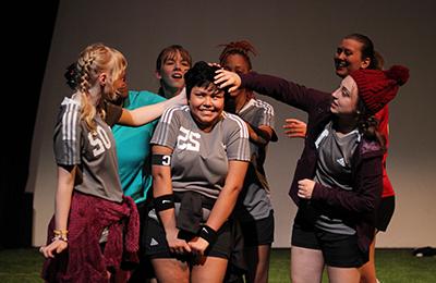 学生 in soccer uniforms performing a play.